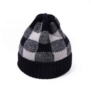 Detail view of the black and white checkerboard knit pattern and ribbed cuff on the beanie