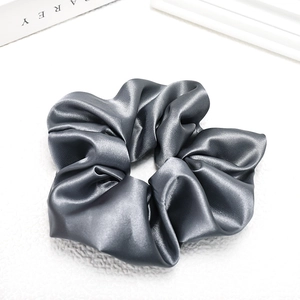 Macro detail of glossy grey satin scrunchie showing smooth texture and soft folds