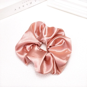 Detailed close-up of glossy pink satin scrunchie showing smooth silky fabric texture