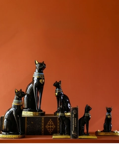 Detailed view of Bastet Egyptian cat bookends and resin candle holders on vintage books