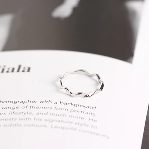 Detailed view of silver S925 sterling silver wavy twisted Mobius ring on an open book
