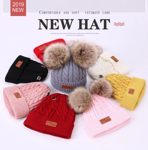 Detailed close-up showing multiple colors of knitted winter beanies with double pom-poms