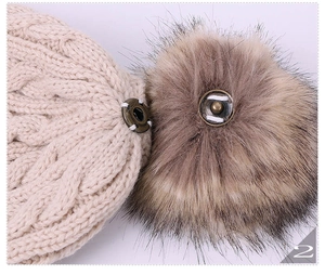 Macro detail of metal snap button for detachable fur pompom on beige cable knit hat