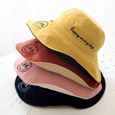 Dettaglio di cappelli da sole colorati con ricamo smiley e happy everyday in quattro colori