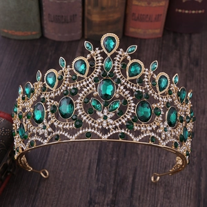 Detailed macro shot of vintage gold crown featuring large green emerald gems and white crystals