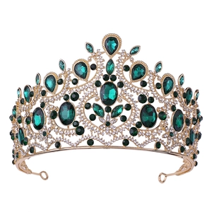 Macro detail of golden baroque crown featuring emerald green gemstones and clear rhinestones