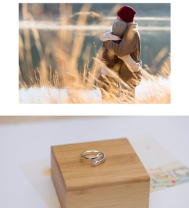 Close-up of silver-plated hugging hands ring on wood with a warm couple background