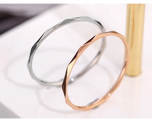 Macro shot of silver and rose gold bangles with geometric diamond-cut faceted texture