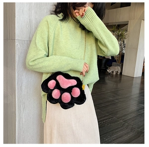 Detail of plush cat paw crossbody bag with black fur, pink pads and metal chain strap