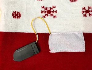 Detail of the LED battery switch box and wires hidden in a knitted Christmas hat pocket