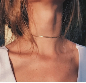 Detail shot of a minimalist 18K gold-plated flat snake chain choker on model neck
