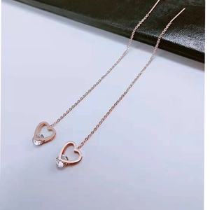 Macro detail of rose gold heart threader earrings with clear crystal stone inlay