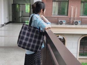 Detail of the navy blue plaid tote bag with sturdy black leather shoulder straps