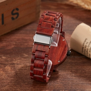 Detail of red sandalwood watch band with polished metal folding clasp on wood surface