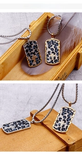 Close-up of leopard print rectangle dog tag pendants with cross detail on bead chains
