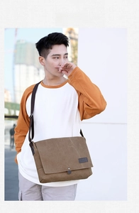 Brown vintage canvas messenger bag for men shown on shoulder in outdoor urban setting