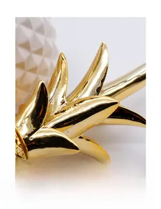 Close-up of golden metallic pineapple leaves and white geometric ceramic texture
