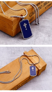 Macro detail of blue dog tag pendant with silver cross on industrial box chain