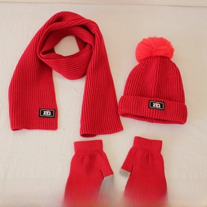 Detail of red knitted winter set for kids featuring warm scarf, beanie hat, and gloves