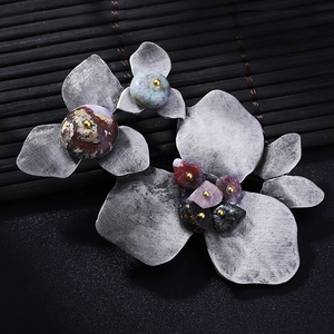 Vintage silver flower brooch with natural stones on a bamboo mat, retro leaf style