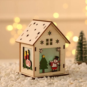 Lighted wooden Christmas house decoration with snowman and star cutouts on white stones