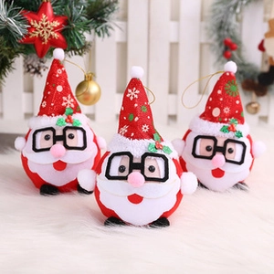 Three Santa Claus plush ornaments with glasses on a white fur rug with a Christmas tree