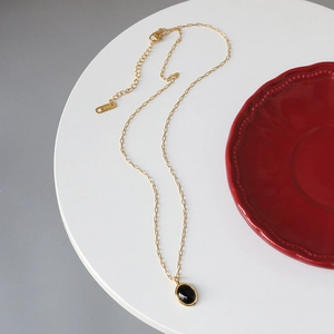 Detailed view of gold necklace with oval black opal pendant and K18 metal tag