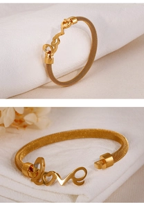 Detail of a golden mesh titanium steel bracelet featuring a Love script and heart charm