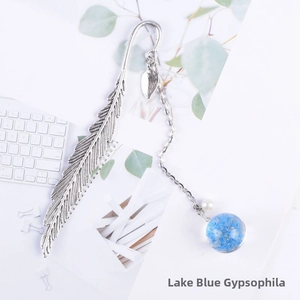 Detailed shot of silver feather bookmark with pearl and blue dried flower glass charm