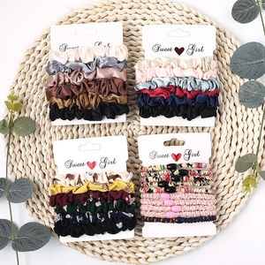 Detail of silk-satin scrunchie sets in solid candy colors and floral patterns on straw mat