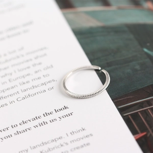 Detail view of silver minimalist beaded open ring on an open book page