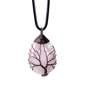 Macro detail of teardrop pink crystal pendant with bronze wire-wrapped tree of life design