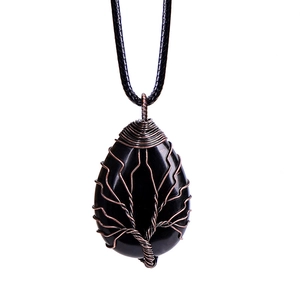 Macro detail of wire-wrapped tree of life on teardrop black stone pendant necklace