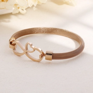Bracciale a maglia oro rosa con ciondolo infinito a cuore su superficie minimalista