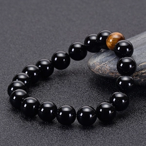 Detail of high-quality black agate beads with brown tiger eye stone on a grey rock surface