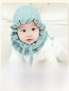 Close-up of mint green knitted baby bonnet with ruffle edges and soft chin straps