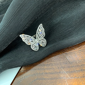 Detail of silver butterfly ring with sparkling cubic zirconia on wood background