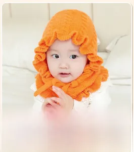 Detail of warm orange knitted baby bonnet with ruffled edges and secure chin strap tie