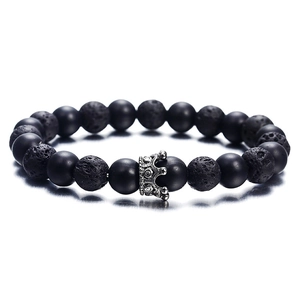 Matte black agate and volcanic stone beaded bracelet with silver crown charm on white background
