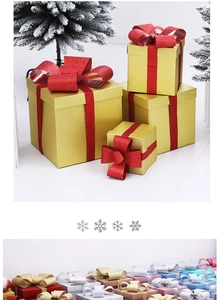 Detail of glitter gold Christmas gift boxes with red ribbons in a winter snow setting