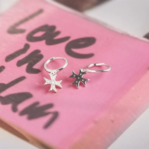 Macro detail of S925 sterling silver hoop earrings with a cross star cubic zirconia charm