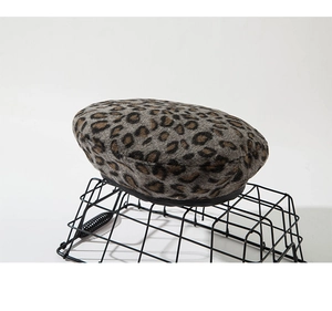 Detail shot of leopard print beret with soft plush texture and black piped edge trim