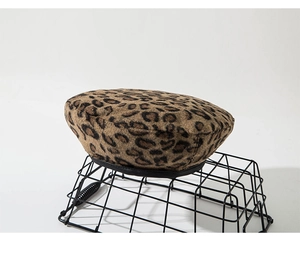 Close-up of leopard print wool beret featuring retro black leather trim and soft texture