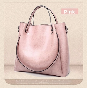 Detail of pink vintage bucket bag showing natural pebble leather texture and metal handle accents