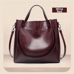 Detailed view of dark burgundy bucket bag with litchi texture and silver rivet handles