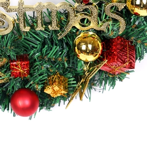 Détail d'une couronne de Noël avec aiguilles de pin, boules rouges et texte doré