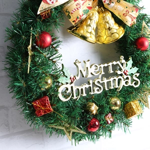Détail d'une couronne de Noël verte avec un nœud doré, des cloches et Merry Christmas