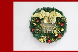 Détail d'une couronne de Noël verte avec cloches dorées, boules rouges et nœud brillant