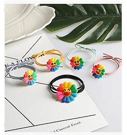 Close-up of five colorful rainbow sunflower scrunchies with smiling face pendants