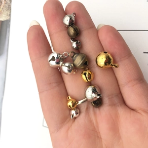Close-up of assorted DIY metal bells in gold, silver, and bronze finishes held in hand